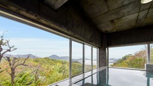 Una piscina interior moderna con grandes ventanales que ofrecen vistas a un paisaje montañoso.