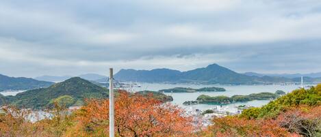A scenic view of a coastal area with mountains, a bridge, and autumn foliage.