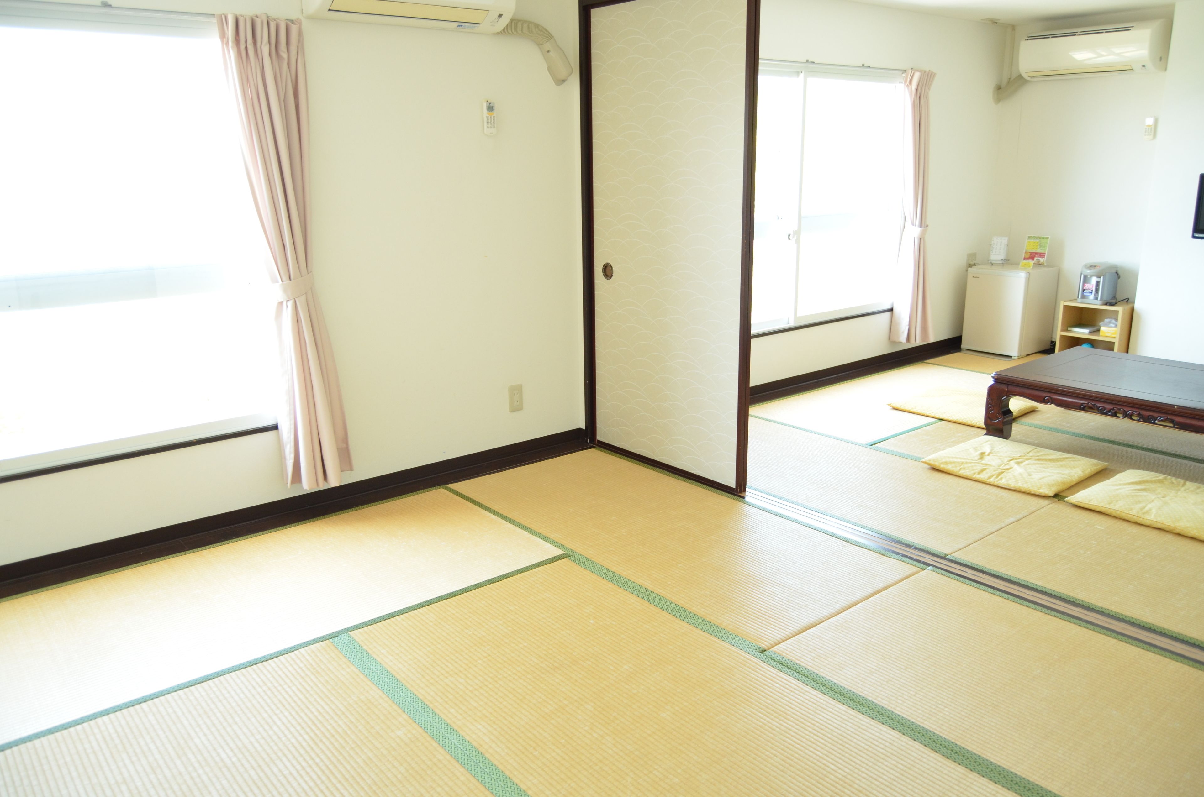 Una habitación japonesa tradicional con suelo de tatami, un puertas correderas y una mesita.
