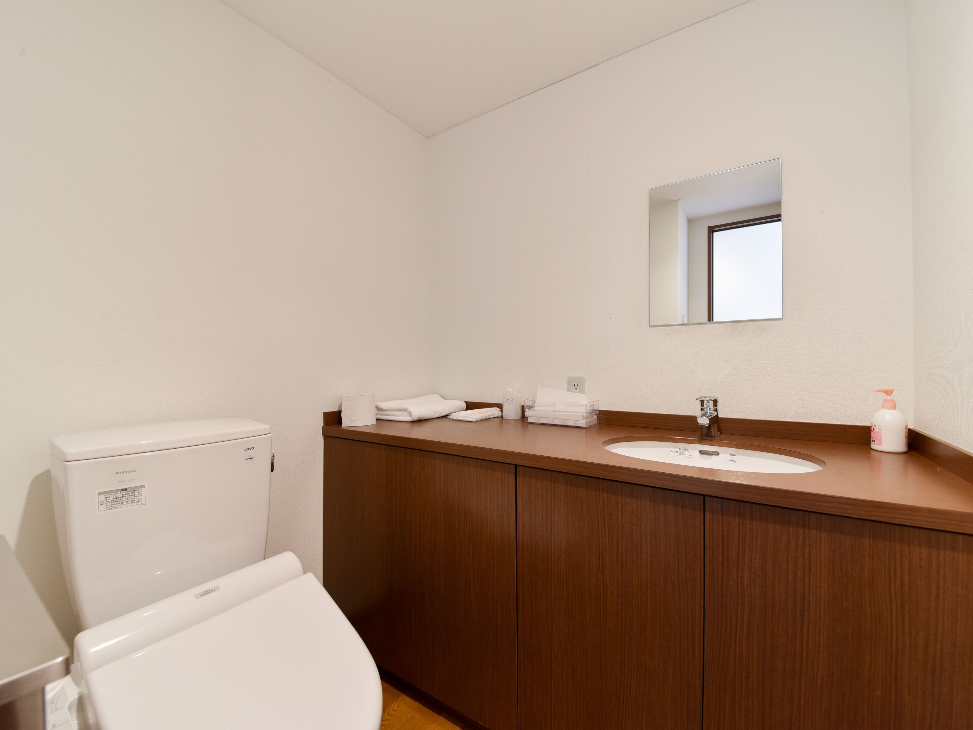 Ein Badezimmer mit einer weißen Toilette, einem Holzwaschtisch mit einem Waschbecken und einem Spiegel über dem Spiegel.