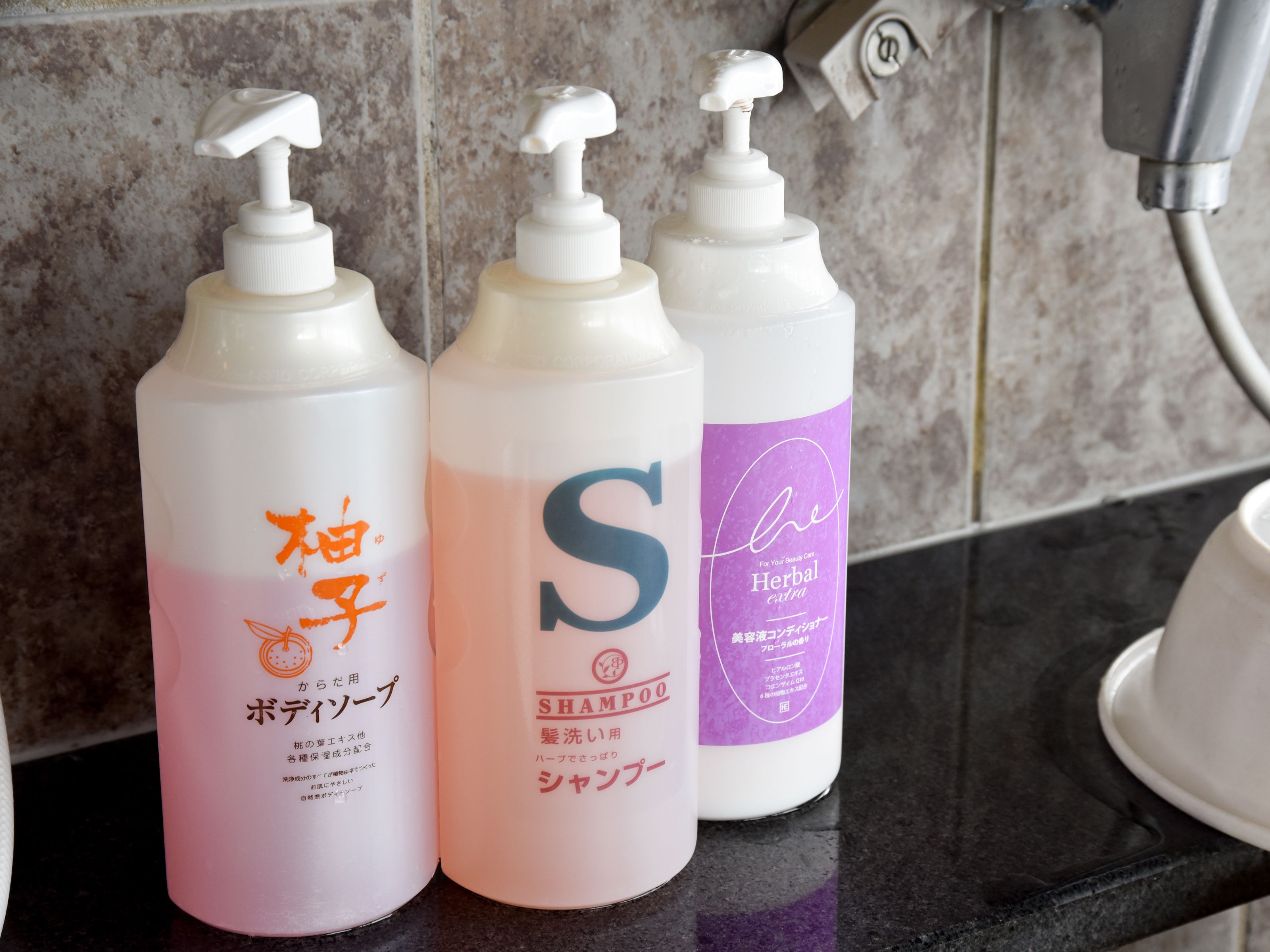 Three bottles of shampoo on a bathroom counter.