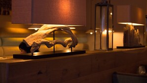 A wooden reception desk with a large, illuminated lamp above it, a glass display case with a sculpture, and a wall-mounted lamp.