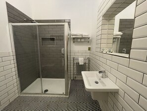 Bathroom features a shower area with a glass door and a geometric-patterned floor.