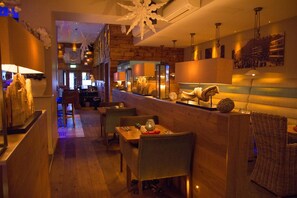 Welcome to our hotel lobby, featuring a comfortable seating area with upholstered chairs and a long counter with decorative items.