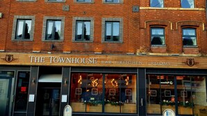 A brick building with a sign reading "The Townhouse Bar, Kitchen, Rooms".