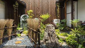 A traditional Japanese garden with a wooden fence, bamboo plants, rocks, and a small waterfall. - Higashiyama Jin (Kyoto)
