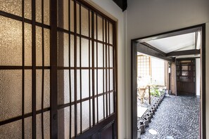 A traditional Japanese interior with a tatami mat floor, a sliding door with a frosted glass panel, and a wooden ceiling structure. - Higashiyama Jin (Kyoto)