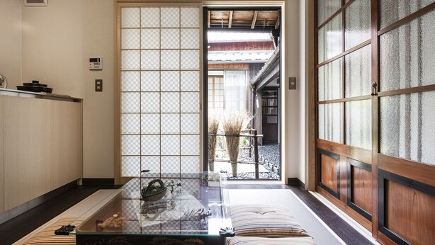 A traditional Japanese room with tatami flooring, a low table with a glass top, and sliding doors with frosted glass panels. - Higashiyama Jin (Kyoto)