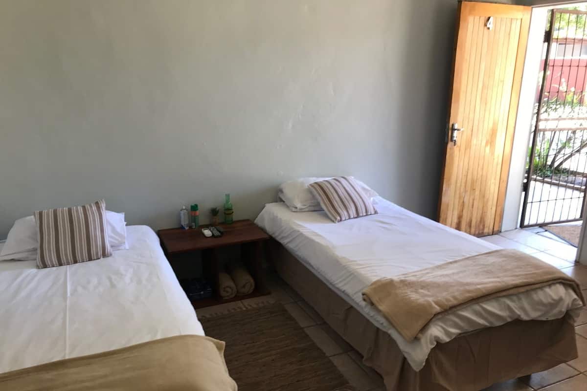 A room with two beds, a wooden door, and a small table with toiletries.
