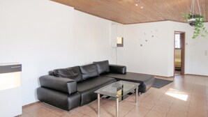 Un salon moderne avec un canapé d’angle, une table basse en verre et un design minimaliste.