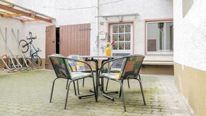 Une cour avec une table et des chaises, un vélo et une fenêtre donnant sur un beau paysage.