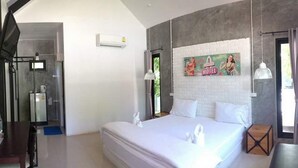 A bedroom with a large bed, a shower area, and a wall-mounted air conditioner. - The Lighthouse Resort At Chanthaburi (Chanthaburi)