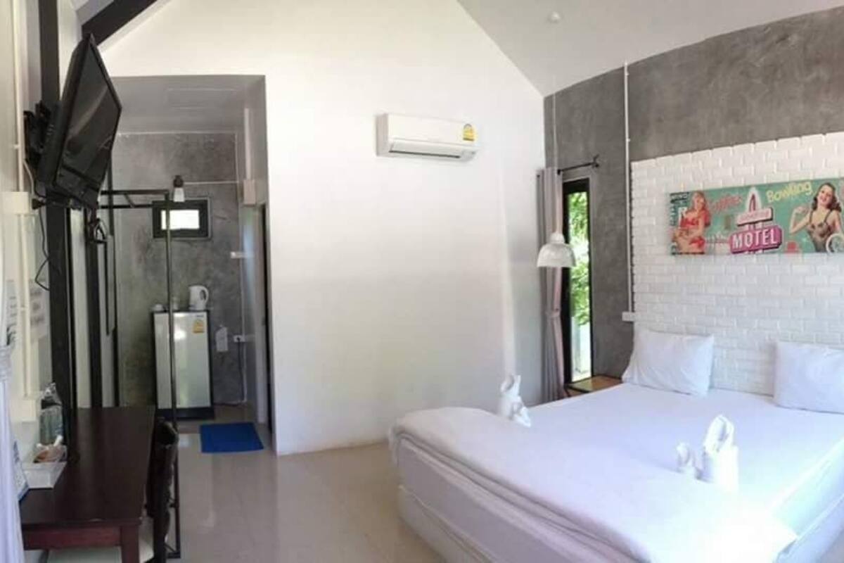A bedroom with a large bed, a shower area, and a wall-mounted air conditioner.