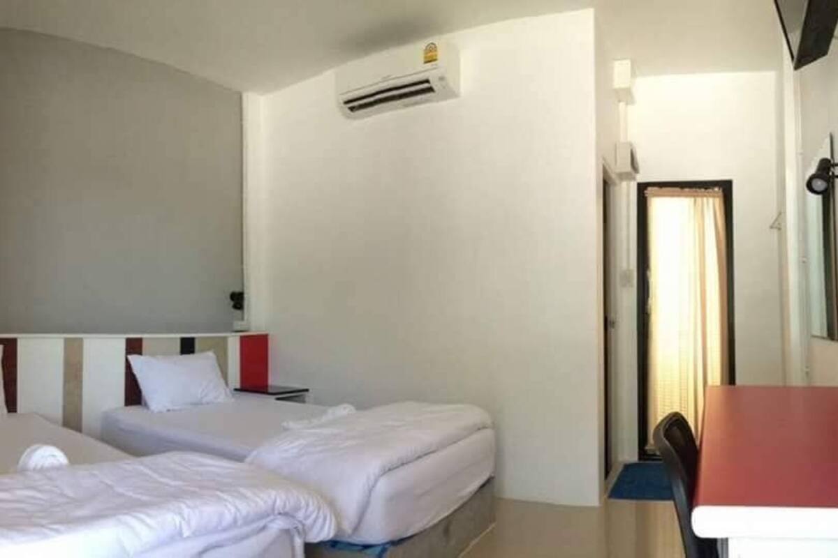 A hotel room with two beds, a desk, and a chair.