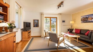 Ein Wohnzimmer mit einer Couch, einem Couchtisch, einem Fernseher und einem Bücherregal.
