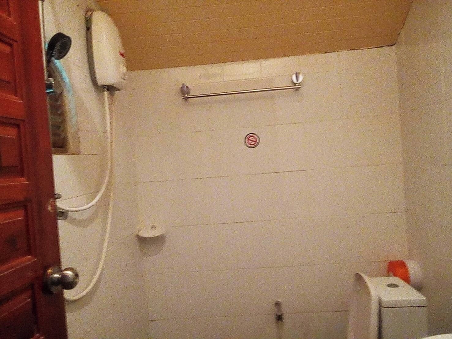 A small, enclosed bathroom with a shower, a towel rack, and a toilet.