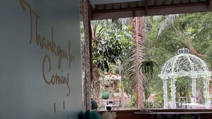 A room with a large window, a wall with 'Thank you for coming' written on it, and a small garden visible through the window.