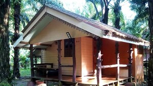 A rustic cabin with a porch, wooden beams, and a small window.