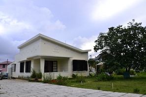 A two-story building with a flat roof, a covered porch, and a garden with various plants and flowers. - 69 Lugia House (Lam Vien - Da Lat)