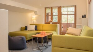 Ein modernes Wohnzimmer mit einem gelben Sofa, einem kleinen Tisch und einem blauen Sitzsack.