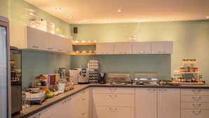 A modern kitchen with white cabinets, a coffee machine, and various food items on the counter. - holiday flat (Siegsdorf)