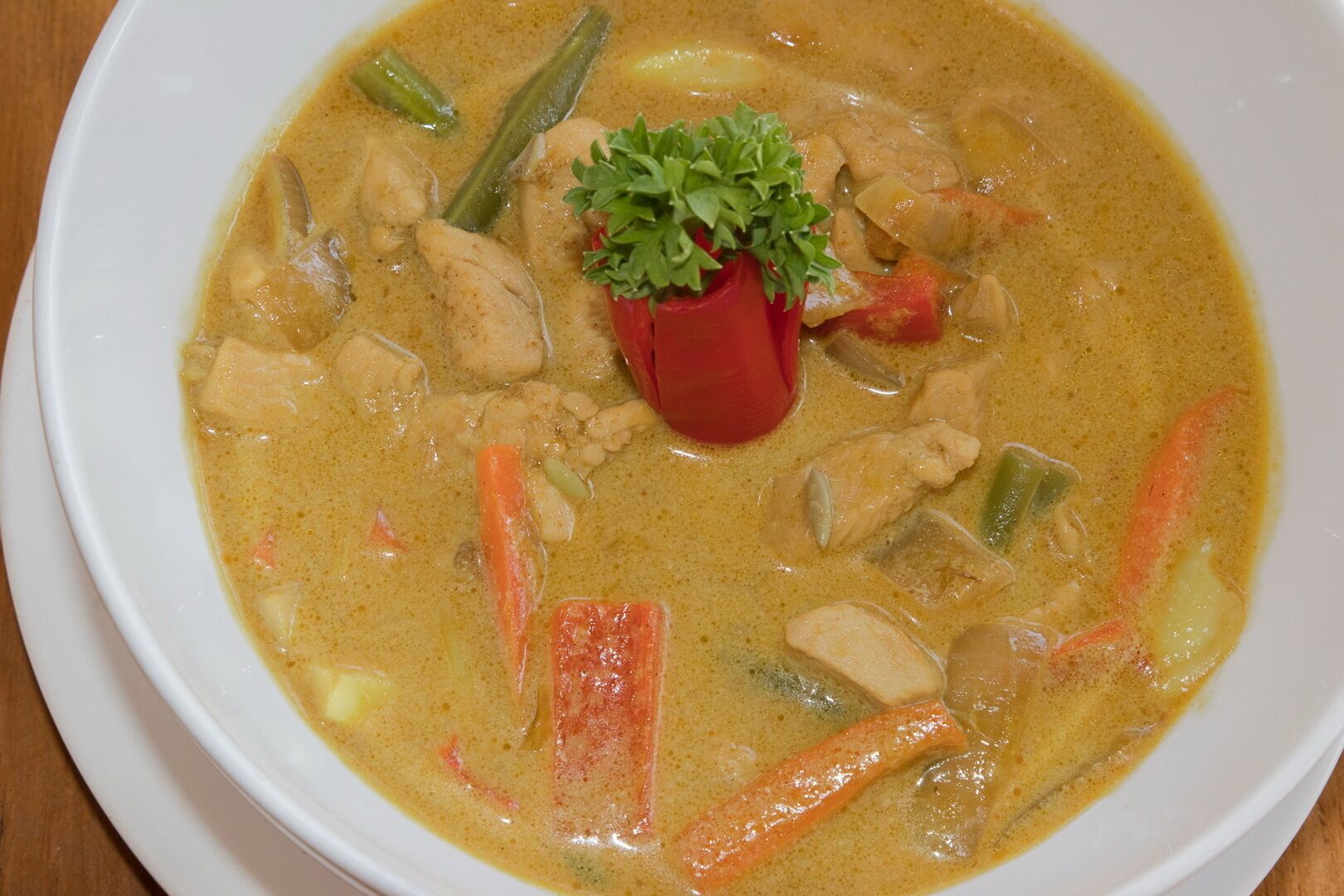 A bowl of soup with vegetables and chicken, garnished with parsley.