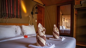 Habitación de hotel con una cama grande, dos toallas de diseño exclusivo, un cabecero de madera y un espejo que refleja la habitación.