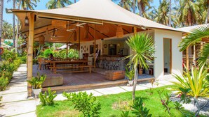 Un espacio al aire libre cubierto con una mesa y sillas, rodeado de abundante follaje y palmeras.