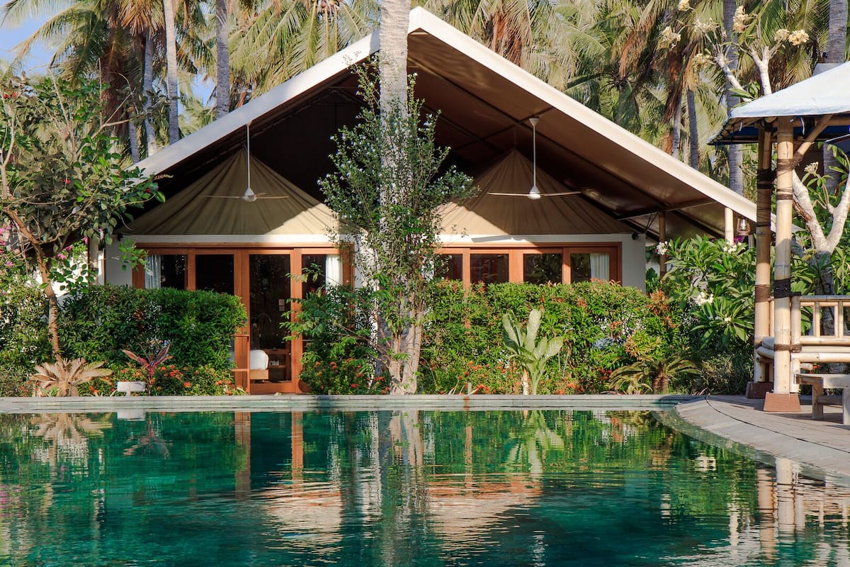 Un complexe hôtelier doté d’une piscine, d’un espace extérieur abrité et d’une végétation tropicale luxuriante.
