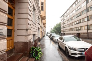 Een smalle straat met geparkeerde auto's en gebouwen met grote ramen.