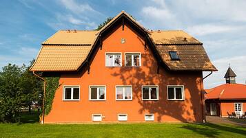 A large, orange house with a steeply pitched roof, multiple windows, and a small tower-like structure on the right.
