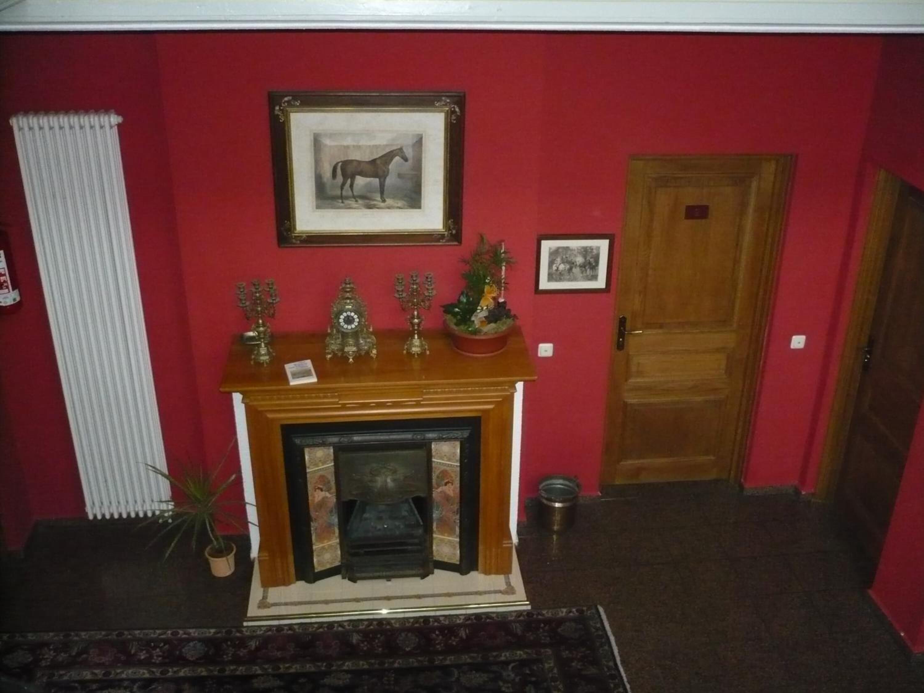 A room with a fireplace, a framed horse picture, and a door.