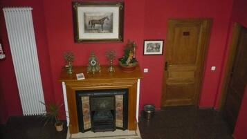 Una habitación con chimenea, un cuadro de un caballo y una puerta.