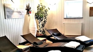 Un cuarto de spa con múltiples sillones reclinables, una planta en maceta y un radiador blanco en la pared.