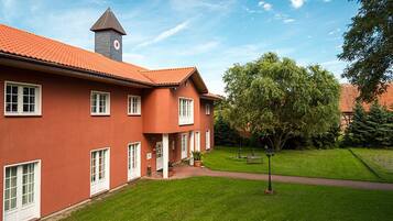 A red building with a clock tower, a well-maintained lawn, and a pathway.