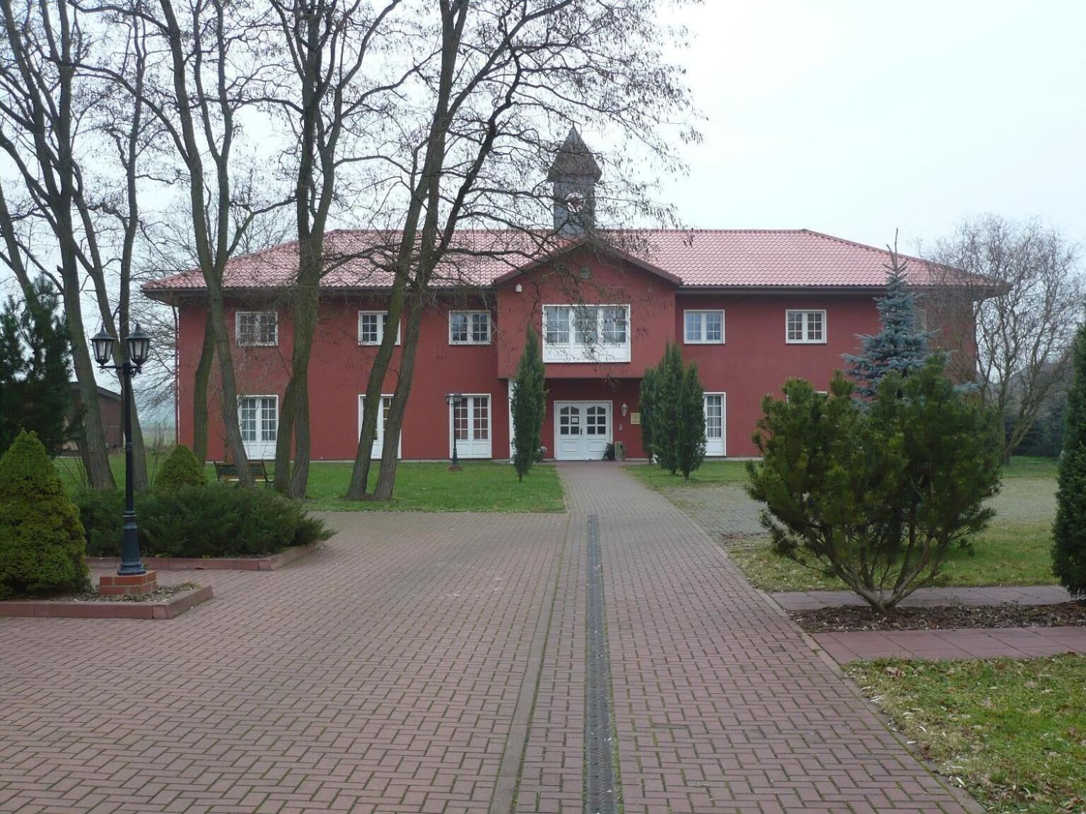 A red brick building with a symmetrical facade, a central entrance, and a small tower.