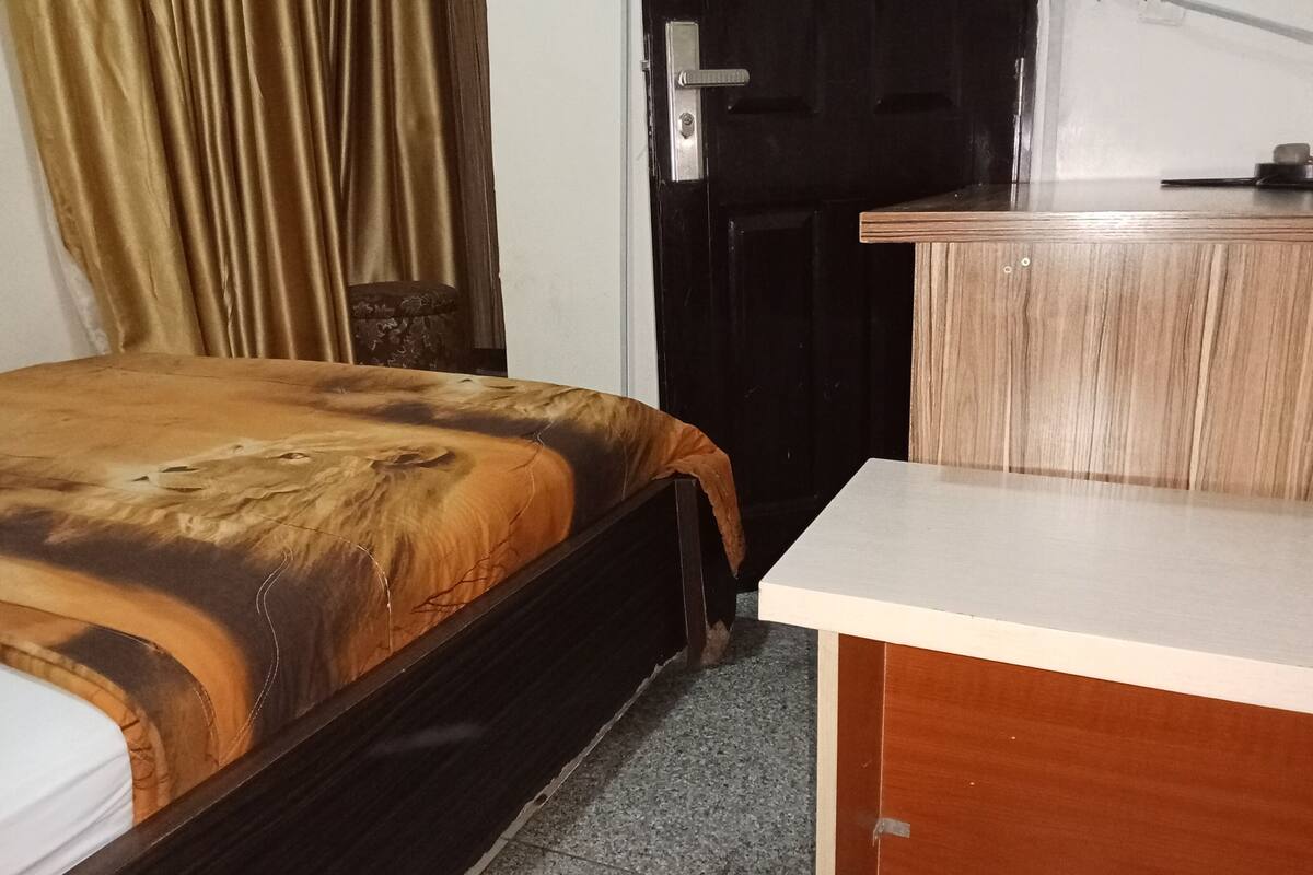 A room with a bed, a desk, a door, and a curtain.