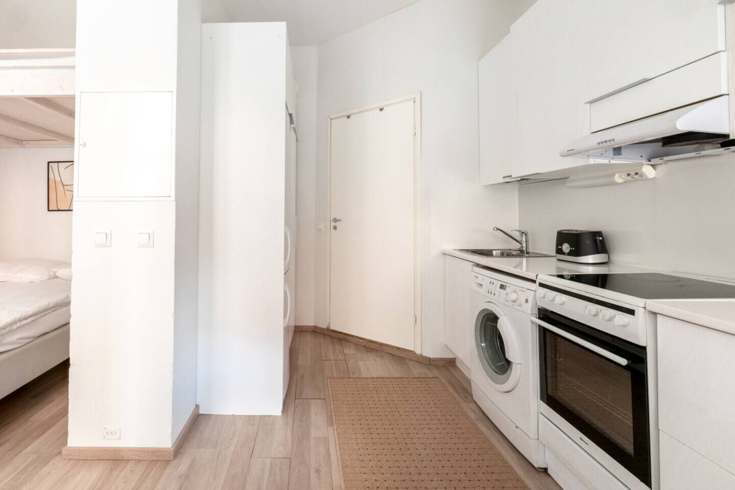 A compact kitchen with a washing machine, oven, and a small countertop.