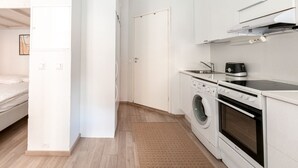 Une cuisine compacte équipée d’un lave-linge, d’un four et d’une machine à café.