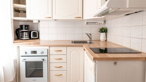 Une cuisine moderne avec des meubles blancs, un four encastré, un four à micro-ondes et un évier.