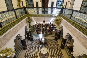 Un amplio patio con una fuente central, barandilla ornamentada y baldosas de diseño.