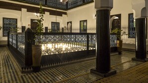 A courtyard with a fountain, ornate metal railings, and tiled flooring. - Riad Ben Tachfine (Marrakech)