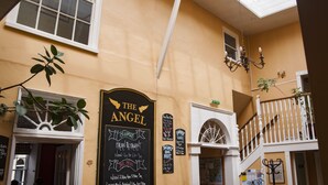 Un restaurante llamado "The Angel" con un menú en una pizarra, un balcón con barandilla blanca y un candelabro.