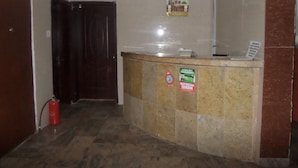 A reception area with a marble counter, a fire extinguisher, and a closed door. - Avery Hotel (Abuja)