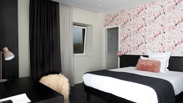 A bedroom with a bed, a desk, a lamp, and a window.