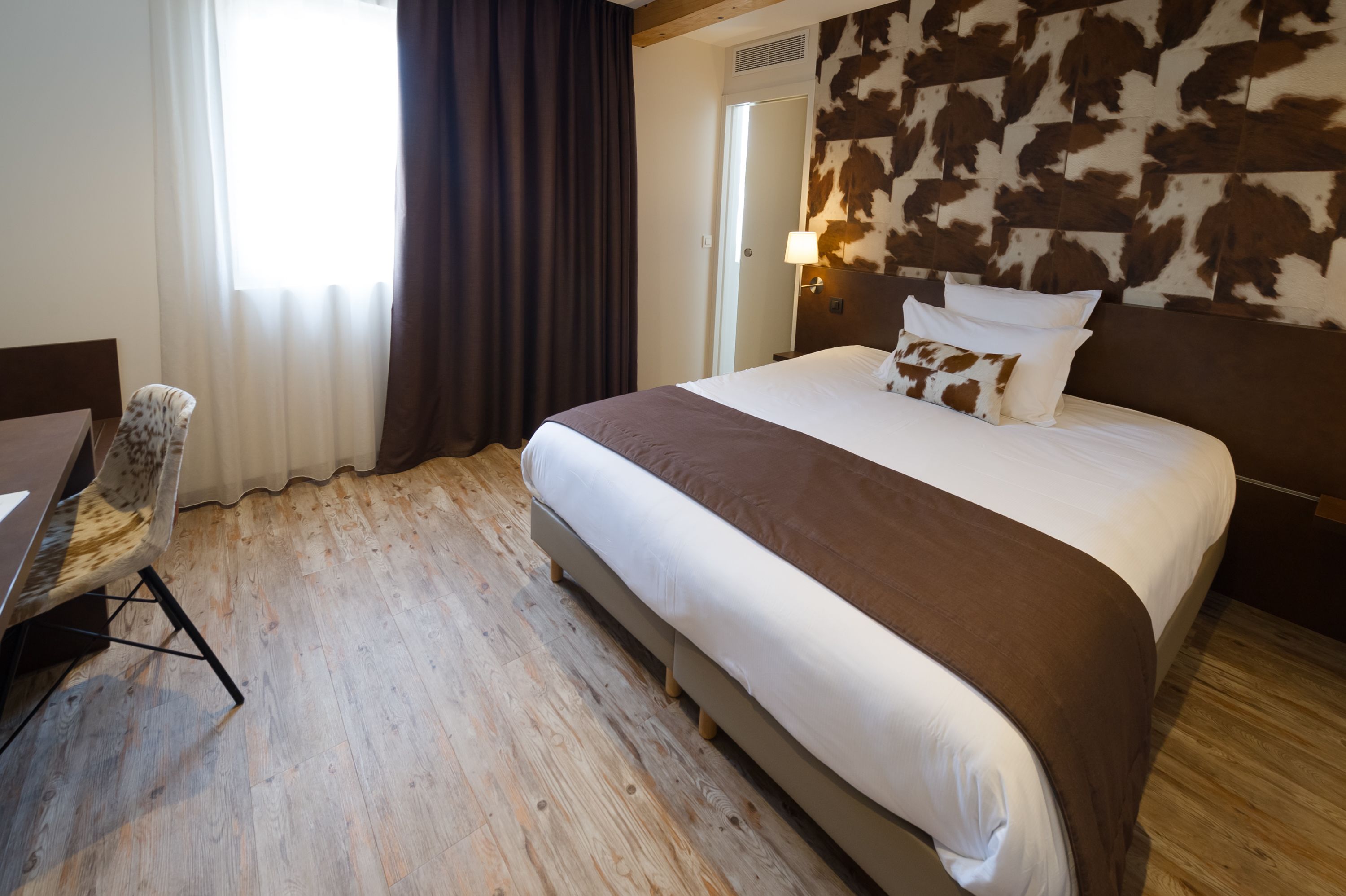 A hotel room with a large bed, a desk, and a chair.