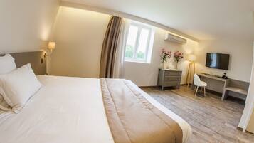 Une chambre d’hôtel avec un grand lit, un bureau, une chaise, une télévision et une fenêtre avec des rideaux.