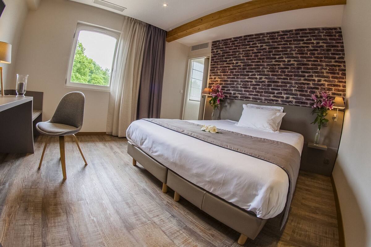 Una habitación de hotel moderna con una cama grande, un escritorio y una ventana con cortinas.