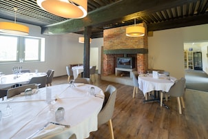 Un restaurante con mesas redondas, sillas y una chimenea de ladrillo.