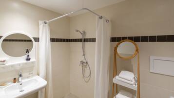 Un baño moderno con ducha, dos lavamanos y un espejo.